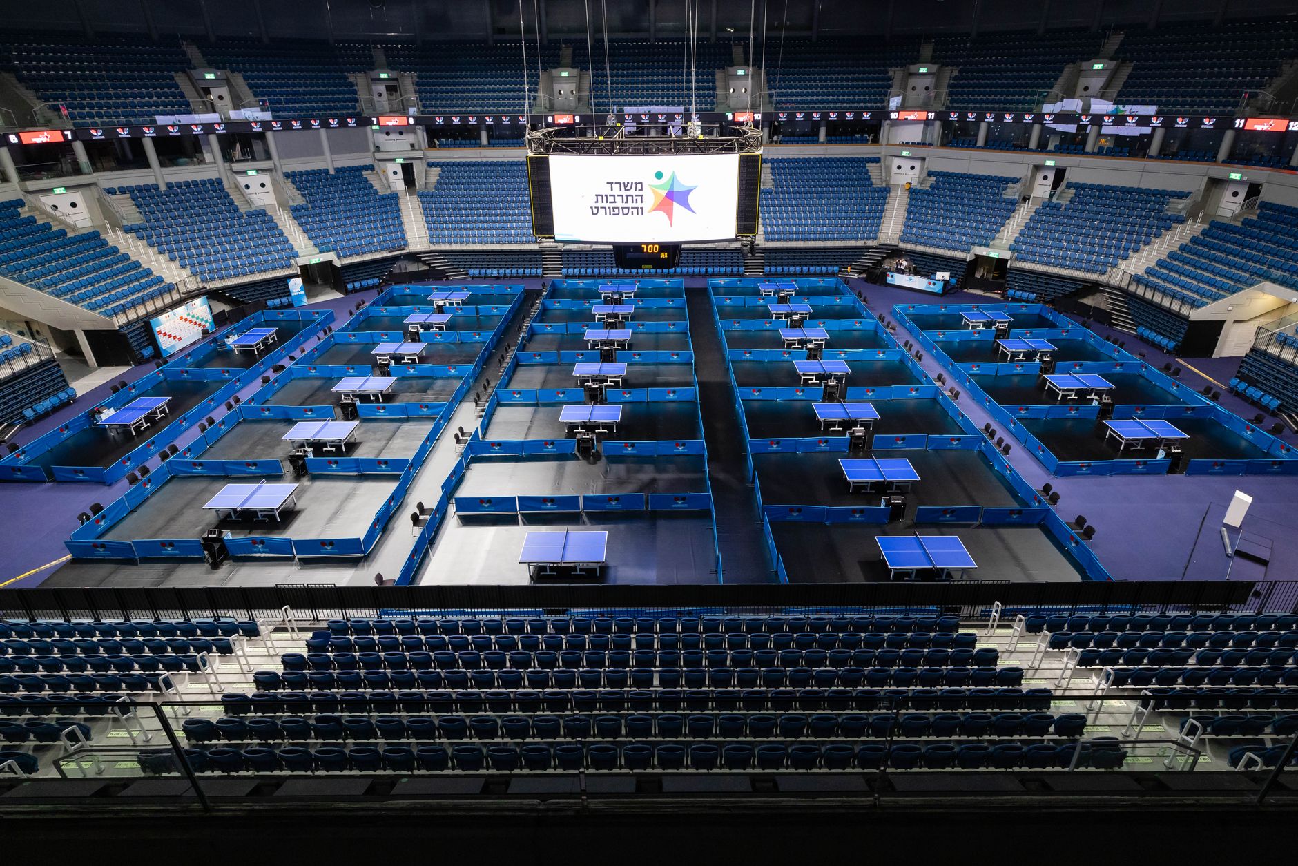 Interior of a huge tennis arena with steep seating tiers, representative of a Grand Slam show court