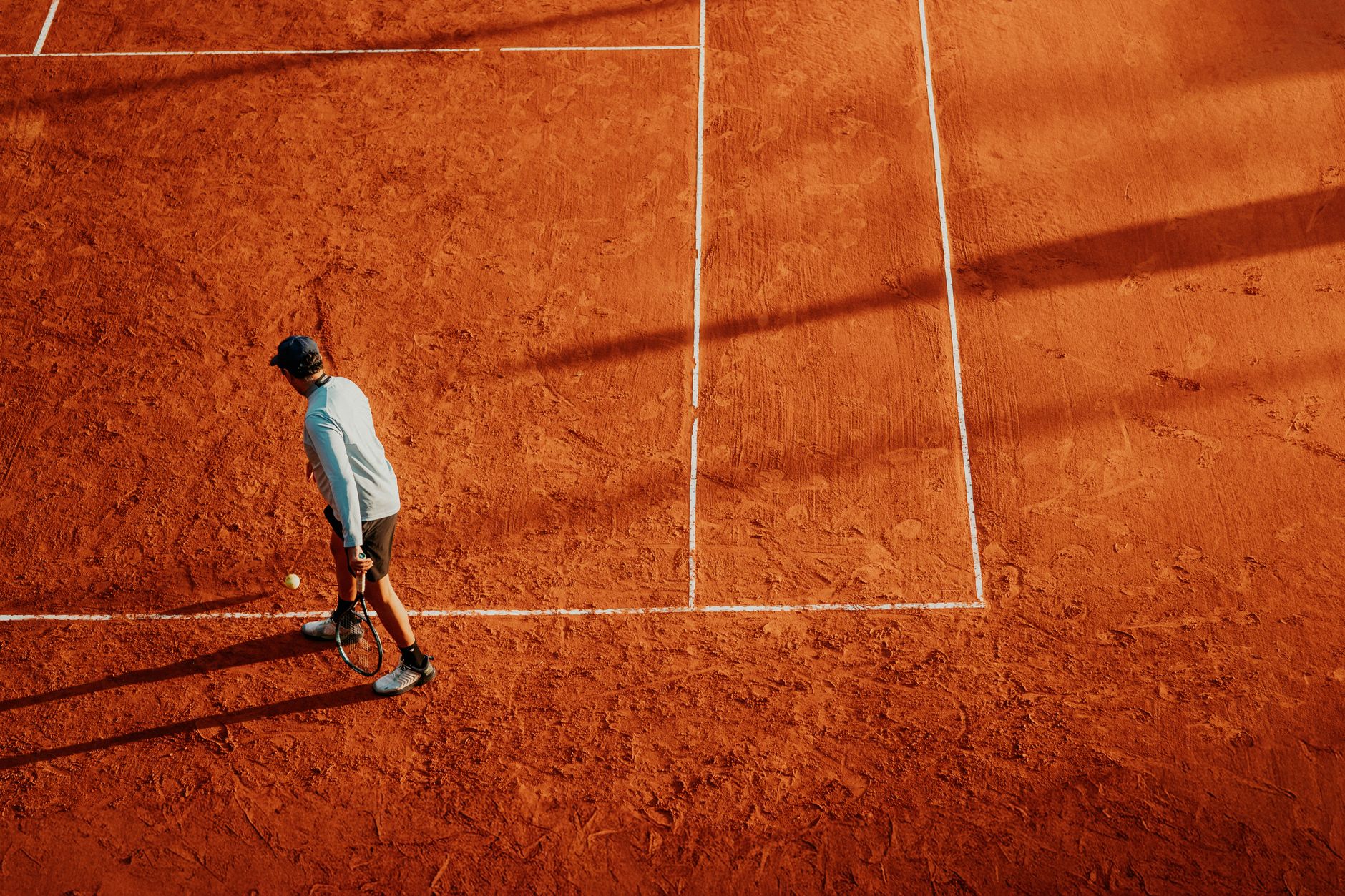 Clay tennis courts with an indoor centre beyond, evoking the multi-surface Centre multiraquettes Montcalm in Québec City